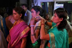 An Indian Hindu widow helps another just before stepping onto the ramp during a fashion show in New Delhi, India, Saturday, Oct. 15, 2016. In most of India, millions of Hindu widows are expected to live out their days in quiet worship, dressed only in white. They are typically barred from all religious festivities because their very presence is considered inauspicious. Their lives appear to be changing for better with women's groups and Indian aid organizations taking interest in their welfare. AP Photo/Altaf Qadri
