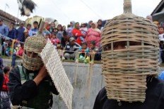 Two participants gear up with bamboo helmets and shields before the tomato fight begins. JP/Arya Dipa