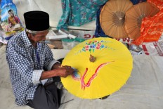 An umbrella maker from Kaliwungu, Kendal, Central Java, decorates an umbrella using oil paints. Customers are primarily attracted to umbrellas painted with flowers and animals. JP / Kus Hendratmo