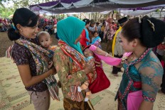 Two women bring their babies forward to ask  for blessings from tayub dancers. JP/ Tarko Sudiarno