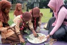 School students who are still in their Pramuka [Indonesian Scout Movement] uniforms collect Asyura porridge leftover. JP/ Theresia Sufa