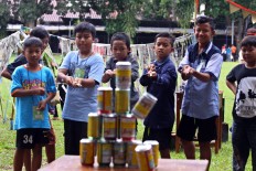 Children use bamboo pipes to hit pyramids of cans with bullets made of wet paper or seeds. The game is played by boys aged 6 to 13 years old.  JP/ Aditya Sagita