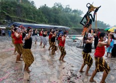 Dressed as the wayang character Petruk, a troupe of young dancers refuses to let the rainy day affect its performance. JP/ Tarko Sudiarno