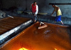 Men stir and tamp down the brown sugar to cool it in a container in a home industry in Genengan village in East Java. JP/ Aman Rochman