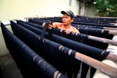 A man checks yarn that is being dried in the sun after dyeing. JP/Aditya Sagita