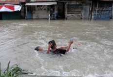 Two children frolic in a flooded road in Jagalan, Jebres in Surakarta, Central Java. JP/ Ganug Nugroho Adi