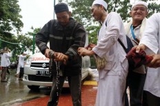 Drenched: A rally participant sueezes out a wet prayer mat after the mass prayer at the National Monument [Monas]. JP/ Seto Wardhana