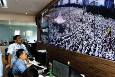 Closely: Acting Jakarta Governor Sumarsono [left] observes thousands of Muslims praying on Friday from the Jakarta Smart City center at City Hall. JP Seto Wardhana