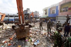 Rescuers use excavators to search for victims under the rubble of collapsed buildings after an earthquake in Pidie Jaya, Aceh. JP/ Hotli Simanjuntak
