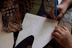 An artisan draws the batik pattern he will apply to his pottery. JP/Ganug Nugroho Adi