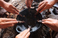 Craftswomen take hot wax from a small wok using a canting [spouted bowl]. JP/Ganug Nugroho Adi