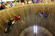Two daredevils ride their motorcycles at high speed on the inside of a barrel in an adrenalin-boosting attraction called “Tong Setan”. JP/Ganug Nugroho Adi
