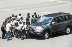 Fighting back: Police officers take cover behind a car while engaging in a gun battle with a group of terrorists on Jl. Thamrin in Central Jakarta on Jan. 14.
