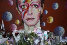 Tributes lie beneath a mural of singer David Bowie by artist Jimmy C in Brixton, South London, the United Kingdom, on Jan. 12. Bowie, the
other-worldly musician who broke pop and rock boundaries with his nonconformity, striking visuals and a genre-spanning persona, and who created Ziggy Stardust, died at age 69 on Jan. 10.