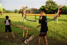Two boys carry tengala and lampit, tools used in makepung lampit, a buffalo race on a wet paddy field in Jembrana. JP/ Agung Parameswara