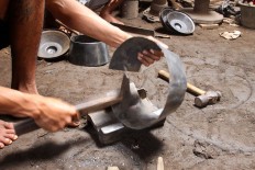 A worker hammers a plate into a kenong percussion set. JP/Aditya Sagita