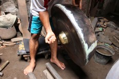 A man tests the sound of a gong after completing the instrument. JP/Aditya Sagita