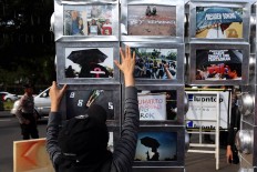 Activists stand next to a photo installation during the 10th commemoration of the Kamisan silent protest in front of the Presidential Palace in Jakarta on Jan. 19. The 477th Kamisan marks the 10th year since the first protest in 2007 asking the government to resolve past human rights violations. JP/Seto Wardhana.