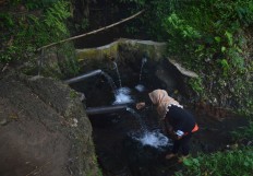 A woman washes her face at Sumber Lanang spring during Malangan mask dance ritual in Malang, East Java. JP/ Aman Rochman