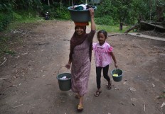 A mother and her daughter carry their clothes to be washed at one of the two springs in the area of Mbah Karimun grave, Pakisaji, Malang, East Java. JP/ Aman Rochman