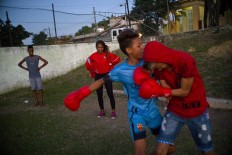 In this Jan. 19, 2017 photo, boxer Idamerys Moreno, center back, looks at children playing around, at a sports center in Havana, Cuba. Boxing has long been an athletic engine for Cuba, which has won 72 Olympic medals in that category but women are not allowed to box. AP/Ramon Espinosa