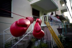 In this Jan. 19, 2017 photo, Idanerys Moreno's boxing gloves hang on a line to dry, after a training session in Havana, Cuba. Women were first allowed to box at the Olympics during the 2012 Summer Olympics but they are still not allowed to box in Cuba. AP/Ramon Espinosa