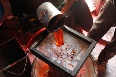 A candle maker pours liquid paraffin wax into a sifter to separate dirt and other unwanted ingredients in Bandung, West Java, ahead of Chinese New Year.  JP/Arya Dipa