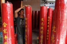 A temple worker places a sticker containing prayer writings on a giant red candle at Dharma Ramsi Temple in Bandung, West Java, ahead of Chinese New Year. Congregation members of the temple can order giant red candles to burn for their individual prayers. JP/Arya Dipa