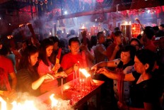 Men and women burn candles during prayers at Toasebio Dharma Jaya Temple in West Jakarta on the eve of Chinese New Year on Jan. 27. JP/Bimo Rahardjo
