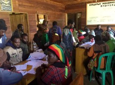 People wait for vote counting at Dikiyouwa village, Kamu district, Dogiyai, Papua. Four polling stations catered to 1,685 voters. The noken system is used in Dikiyouwa, whereby individuals do not go to polling stations to vote. Instead, a tribal leader visits the polling station to lodge one vote to represent every member of his community. JP/Nethy Dharma Somba