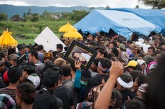 A man carries a framed photograph of a child whose life was claimed in Songan village, Kintamani, Bali, on Monday, February 13, 2017. JP/ Anggara Mahendra