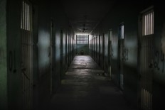 In this Feb. 2, 2017 photo, an inmate sits facing the wall at the end of a corridor between cells at the Monte Cristo agricultural penitentiary in Boa Vista, Brazil. Some prisoners serving time for lesser crimes were forced to participate in gang-driven slaughters that left at least 130 inmates dead in January at this jail, and one other. AP Photo/Felipe Dana