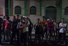 In this Feb. 5, 2017 photo, residents watch police work at a crime scene where a man was murdered in Manaus, Brazil. The increasingly violent city is a thoroughfare for drug trafficking across South America, where authorities suspect most murders are gang related. AP Photo/Felipe Dana