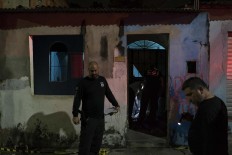 In this Feb. 5, 2017 photo, police inspect a home where a murder victim lies on the floor in Manaus, Brazil. The increasingly violent city is a thoroughfare for drug trafficking across South America, where authorities suspect most murders are gang related. AP Photo/Felipe Dana