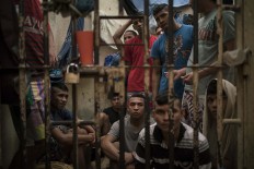 In this Feb. 6, 2017 photo, detainees crowd a holding cell at a police station near Manaus, Brazil. The beginning of the chain that feeds Brazilian gangs are improvised cells at police stations, where 10 percent of Brazil's more than 600,000 inmates await trial. AP Photo/Felipe Dana