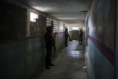 In this Feb. 2, 2017 photo, guards stand outside prison cells at the Monte Cristo agricultural penitentiary in Boa Vista, Brazil. Guards, administrative prison staff and families of inmates of this prison said gang leaders ordered newcomers to join killing sprees in January and dismember and behead the dead. AP Photo/Felipe Dana