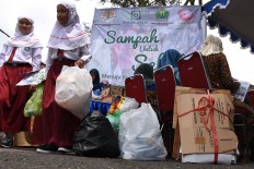 Primary school students and residents bring recyclable trash to get free healthcare services that could cover BPJS Kesehatan premiums. JP/Aman Rochman