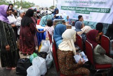 People sit and wait for their turn to submit their recyclable trash in exchange for free healthcare services. JP/Aman Rochman
