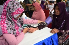 A patient (right) gets her blood pressure checked. JP/ Aman Rochman