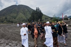 Two Hindu priests and people from the Hindu community walk around the Luhur Poten temple on Mount Bromo. JP/Tarko Sudiarno