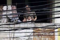 Peek-a-boo: A man and a little boy stand on a balcony facing electrical and phone cables in Jatinegara, East Jakarta. JP/ Dhoni Setiawan