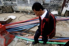 Watch your step: A man walks carefully to avoid cables lying on the road in Matraman, Central Jakarta. JP/ Dhoni Setiawan