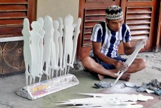 Khotib uses sandpaper to smoothen the wood of wayang klitik. JP/ Magnus Hendratmo