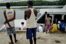 Papuans watch several Balinese Hindus boarding a boat to collect sea water to be used in Melasti rituals. JP/Vembri Waluyas