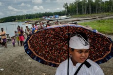 A Balinese Hindu boy uses an umbrella for shelter from the heat. JP/Vembri Waluyas