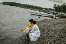 Two women float the offerings out to sea. JP/Vembri Waluyas