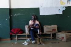 In this April 1, 2017 picture a man takes off his sock after performing as a 'Zarramaco' a character that stains his face in black and rings cowbells in representation of the traditional carnival of La Vijanera de Silio during a gathering of different villages' carnival masks and characters, in Casavieja, Spain, Monday, April 3, 2017. These festivals, held across central and northwestern Spain, most often coincide with festivities celebrating the advent of spring, mixing Carnival and bizarre pagan-like rituals with mock battles between good and evil. AP/Daniel Ochoa de Olza