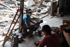 Two men work on making crosses at Widodo’s workshop. JP/Magnus Koeshendratmo