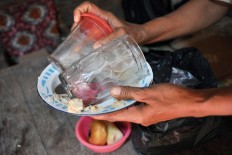 Sugiyem, 70, one of Mbah Jo Gotho's daughters, carries an empty plate and two glasses. Among Mbah Jo Gotho&rsquo;s favorite dishes were tofu and anchovies.  JP/Magnus Hendratmo