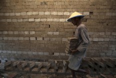 A craftsman moves some dried bricks to be fired after they have been drying under the sun. JP/Sigit Pamungkas